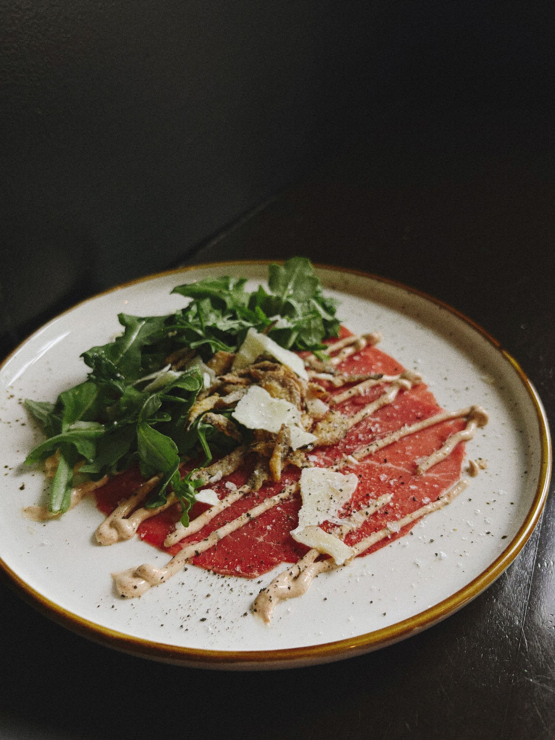 Carpaccio de bœuf, roquette, oignons frits et parmesan, entrée du Club Touriste