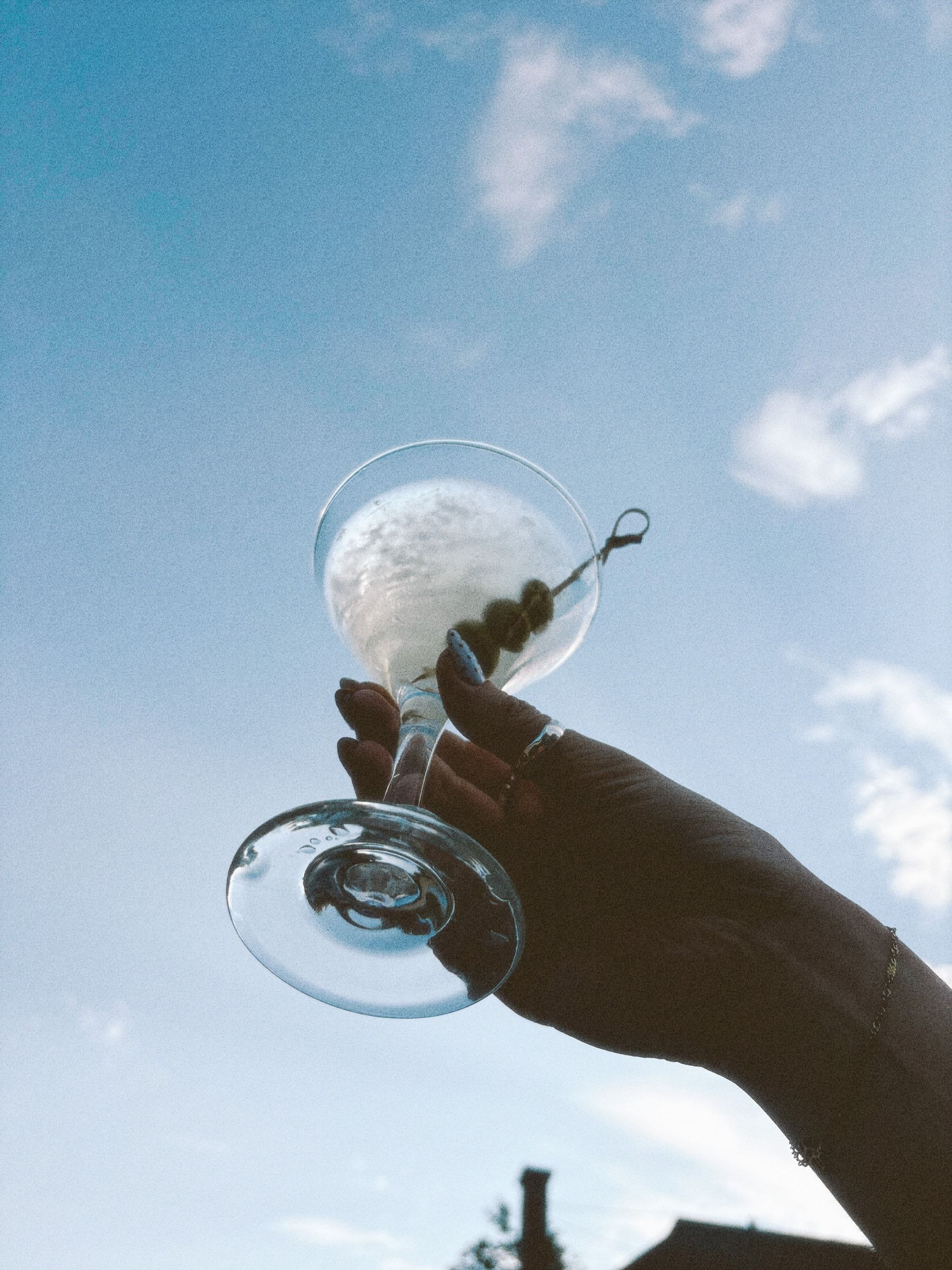 Coupe de martini levée vers le ciel sur la terrasse du Club Touriste