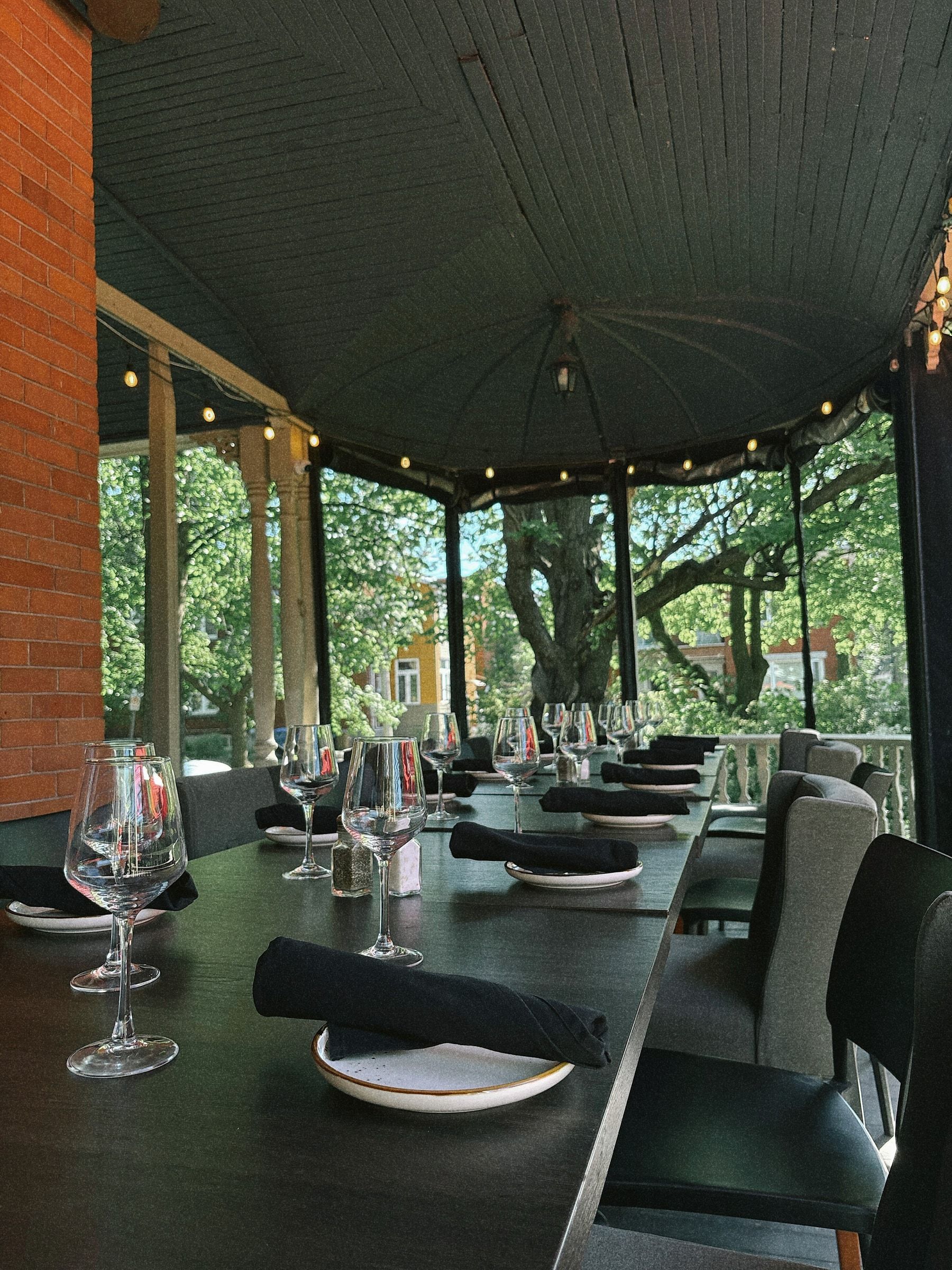 Véranda couverte du Club Touriste avec longue table dressée et guirlandes lumineuses